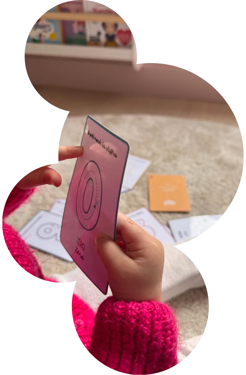 Les mains d'un enfant tenant une carte éducative rose illustrant un chiffre à tracer